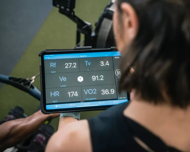 Adult man reviewing fitness metrics on a tablet during a workout session at the gym