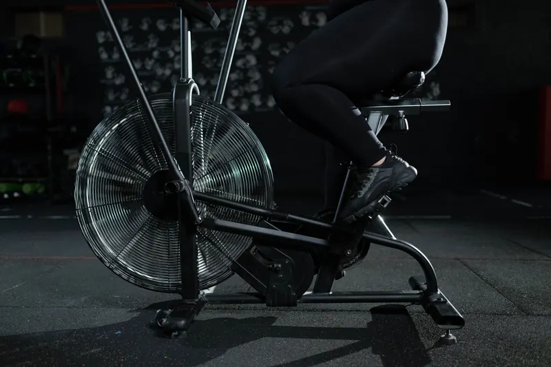 Close-up of a woman exercising on a stationary bike in a dimly lit gym